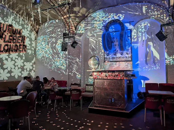 Vaulted room at Donautechno in Vienna with colourful light projections on the walls and a Würstelstand-style booth