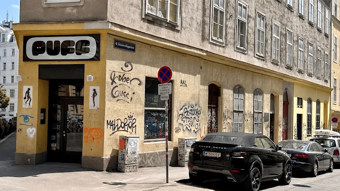 Corner entrance of Puff bar in Vienna with a yellow graffiti-covered facade